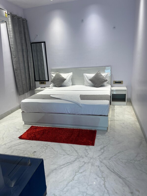 Un dormitorio moderno con una cama grande, una mesita de noche, una alfombra roja y un espejo en la pared.