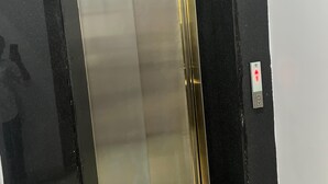 Un ascensor con interior metálico y paredes exteriores negras.