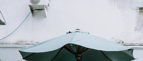 A round wooden table with four chairs and a green umbrella.