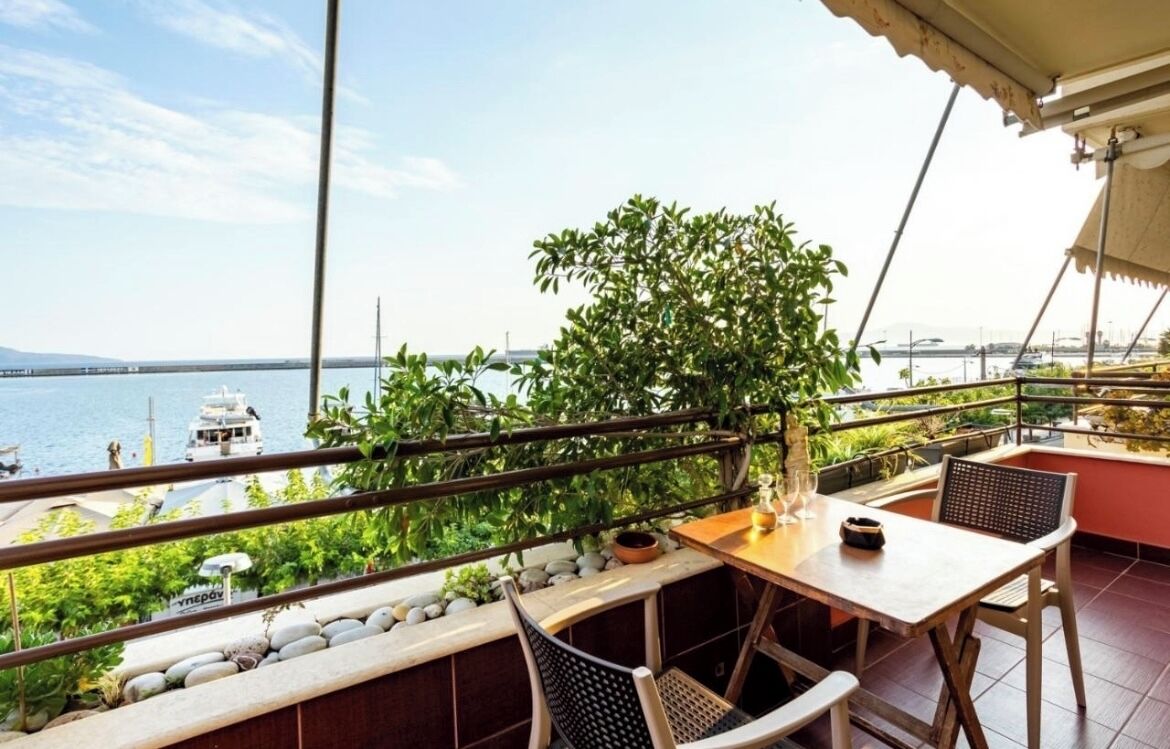 Ein Balkon mit Blick auf das Meer, einem Tisch, Stühlen und einem Blumentopf.