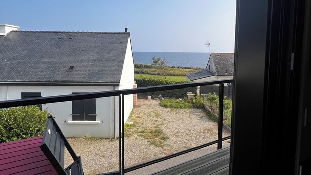 Ein Balkon mit Blick auf ein Haus und das Meer.