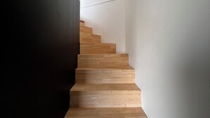 Eine Treppe mit Holzstufen, die nach oben führt, umgeben von schlichten Wänden.