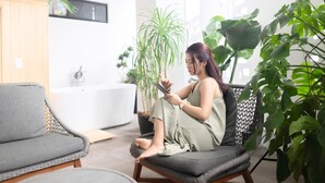 A modern living room with a grey sofa, a wicker chair, and a large potted plant. - 730HOTELS (Ishigaki)