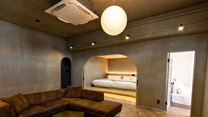 A modern interior with a sectional sofa, a small coffee table, and a bed with a headboard. - 730HOTELS (Ishigaki)