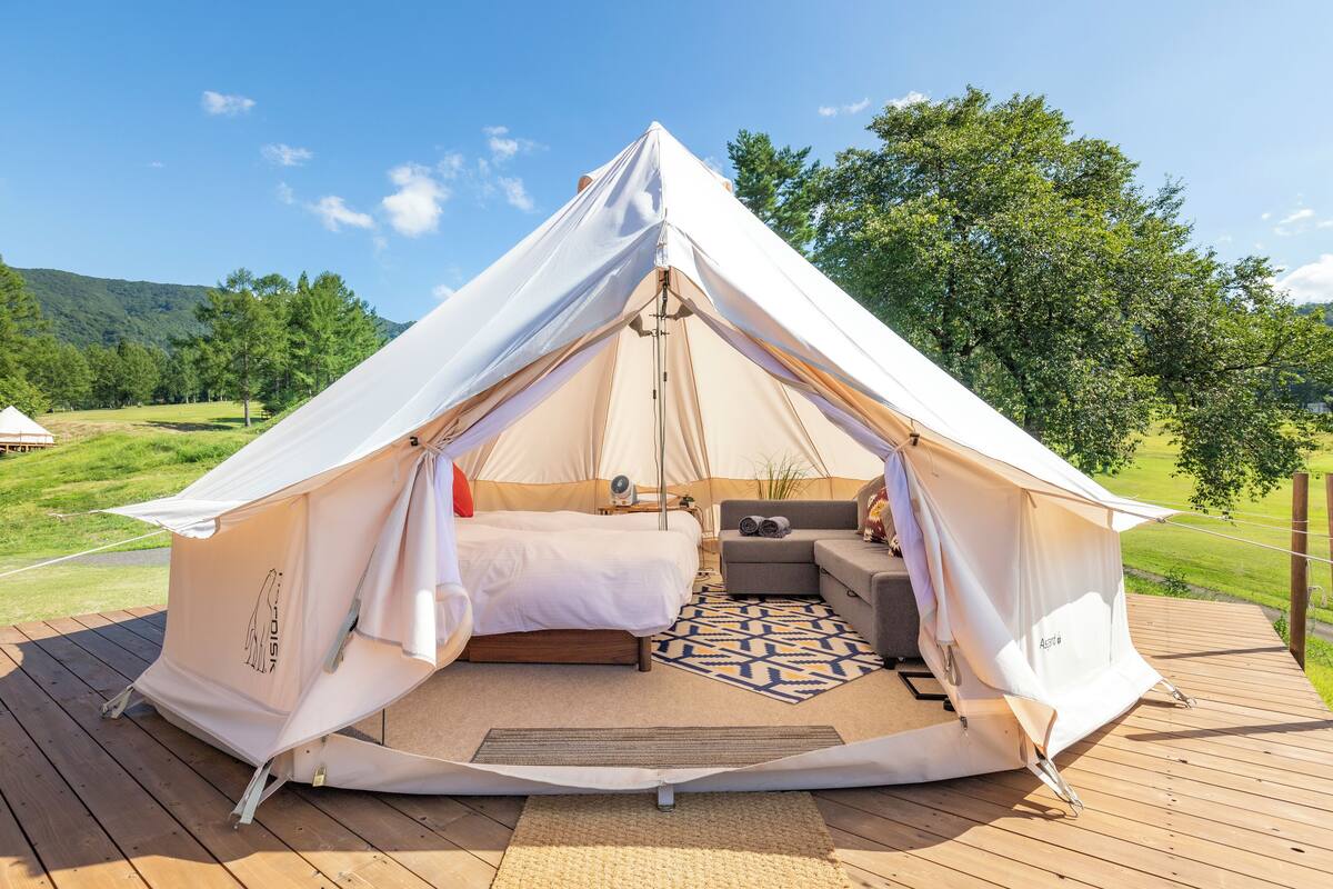 A dome-shaped tent with a bed, seating area, and a small table.