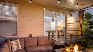 An outdoor patio area with a sofa, a fire pit, and string lights. - Spectacular Hillside Escape w/ Valley Views, Game Room w/ Pool Table and Foosball, Huge Deck / Patio (Beaverton)