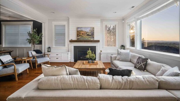A spacious living room with a fireplace, large windows, and a view of the landscape. - Spectacular Hillside Escape w/ Valley Views, Game Room w/ Pool Table and Foosball, Huge Deck / Patio (Beaverton)