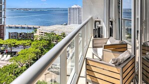 En balkon med udsigt over havet og en høj bygning i baggrunden.