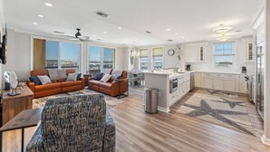 Eine moderne Wohnung mit Wohnbereich, Küche und großen Fenstern.