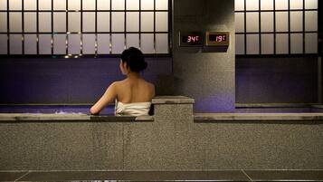 Una persona sentada junto a una piscina, con una pantalla digital que muestra la hora.