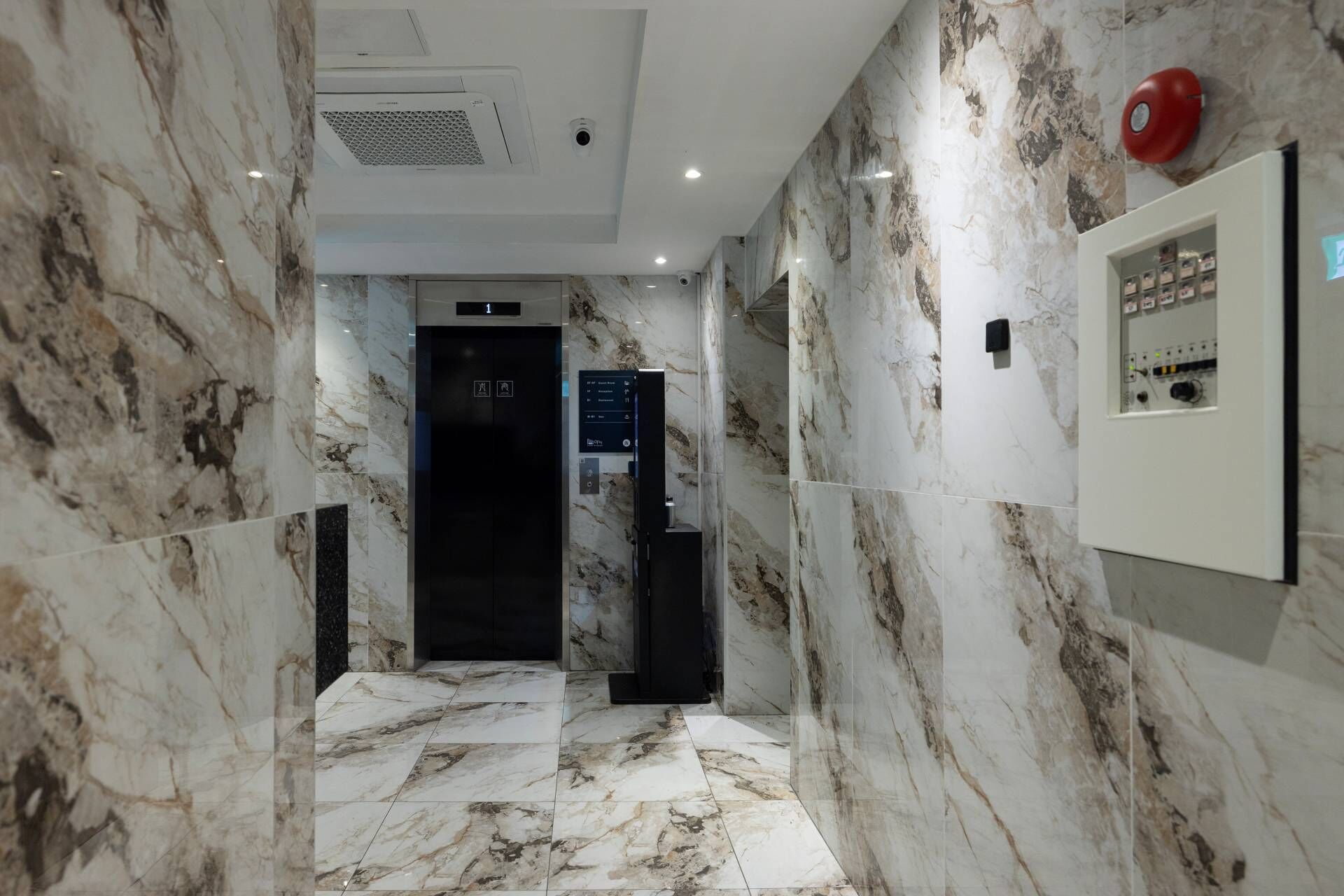 A marble-floored hallway with an elevator and a control panel on the right.
