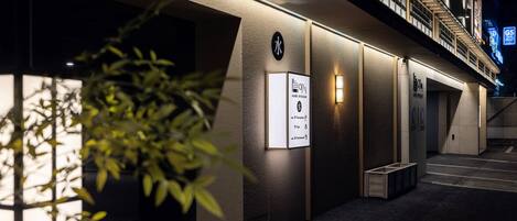 A modern hotel entrance with a staircase, a reception desk, and a sign indicating a 2nd-floor restaurant.