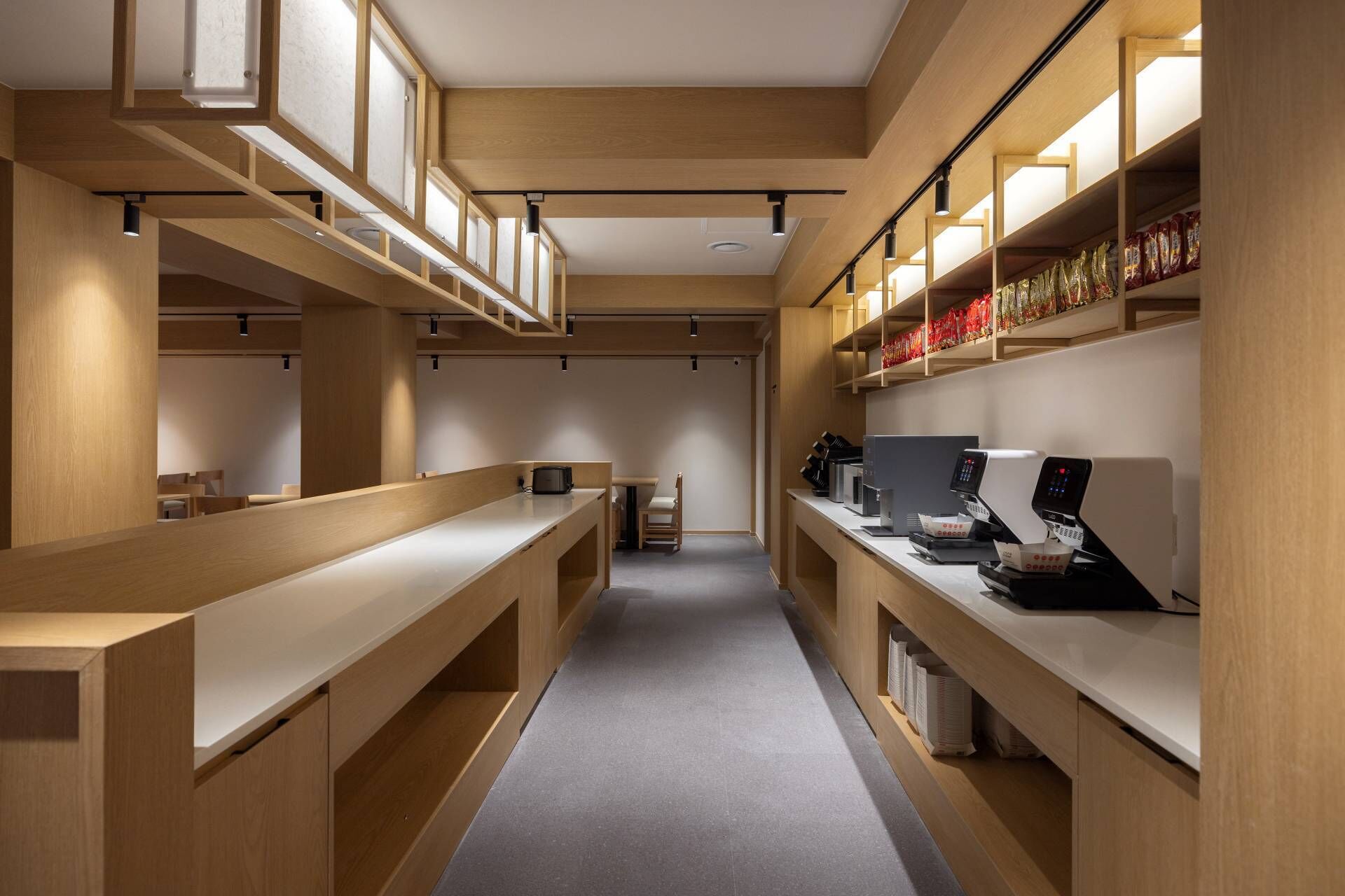 Un café moderne et épuré, avec des meubles en bois et un espace salon central.