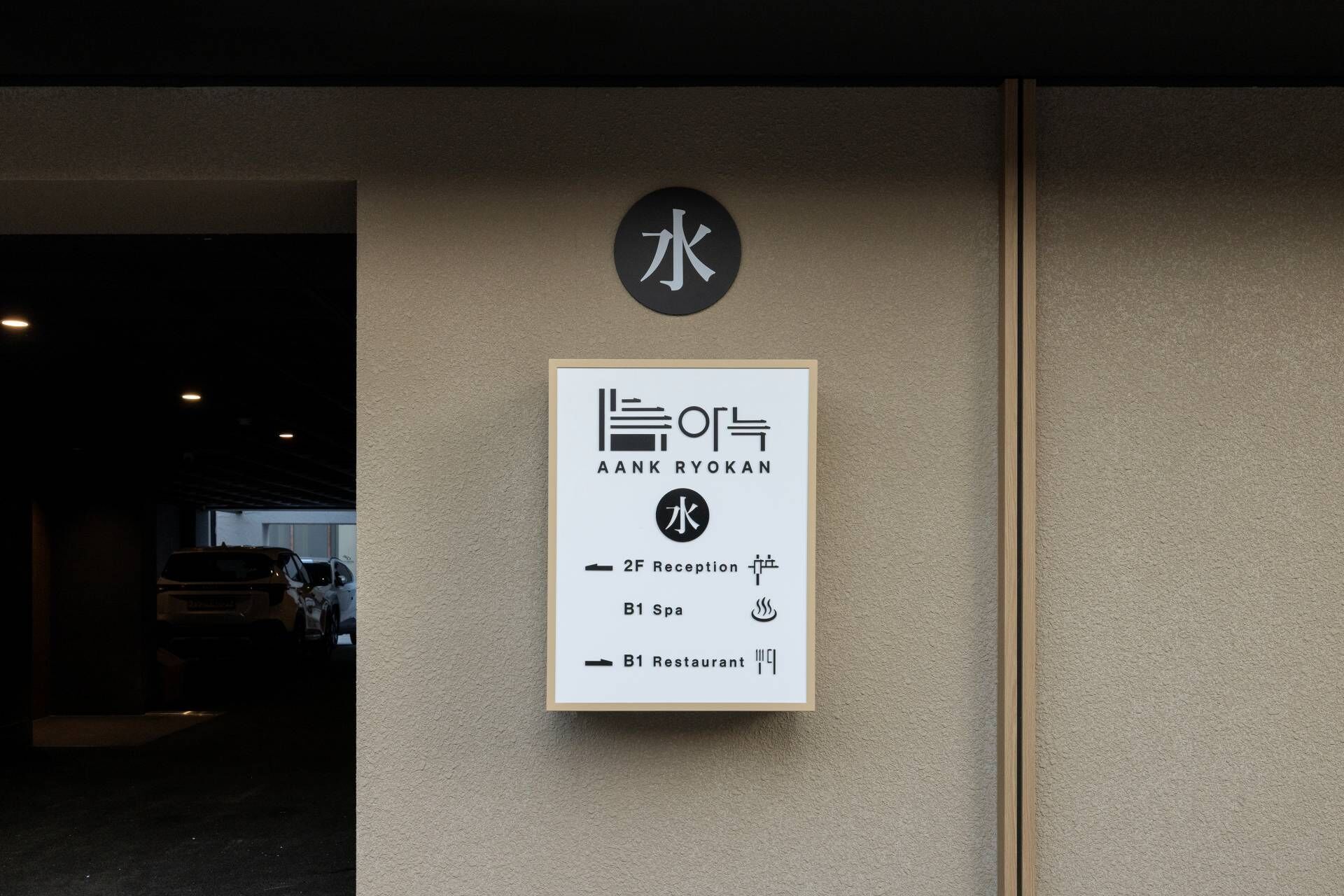 A signboard with the name 'AANK RYOKAN' and icons for a 2F Reception, B1 Spa, and B1 Restaurant.