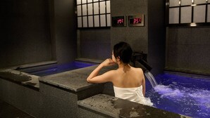 Mulher em banheira de spa com indicadores digitais de temperatura.