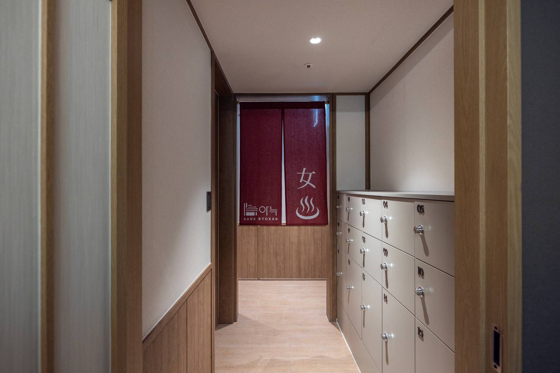 A hallway with lockers on one side and a door with a sign in the center.