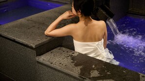 Uma pessoa em um banho de spa com água jorrando de um chuveiro.
