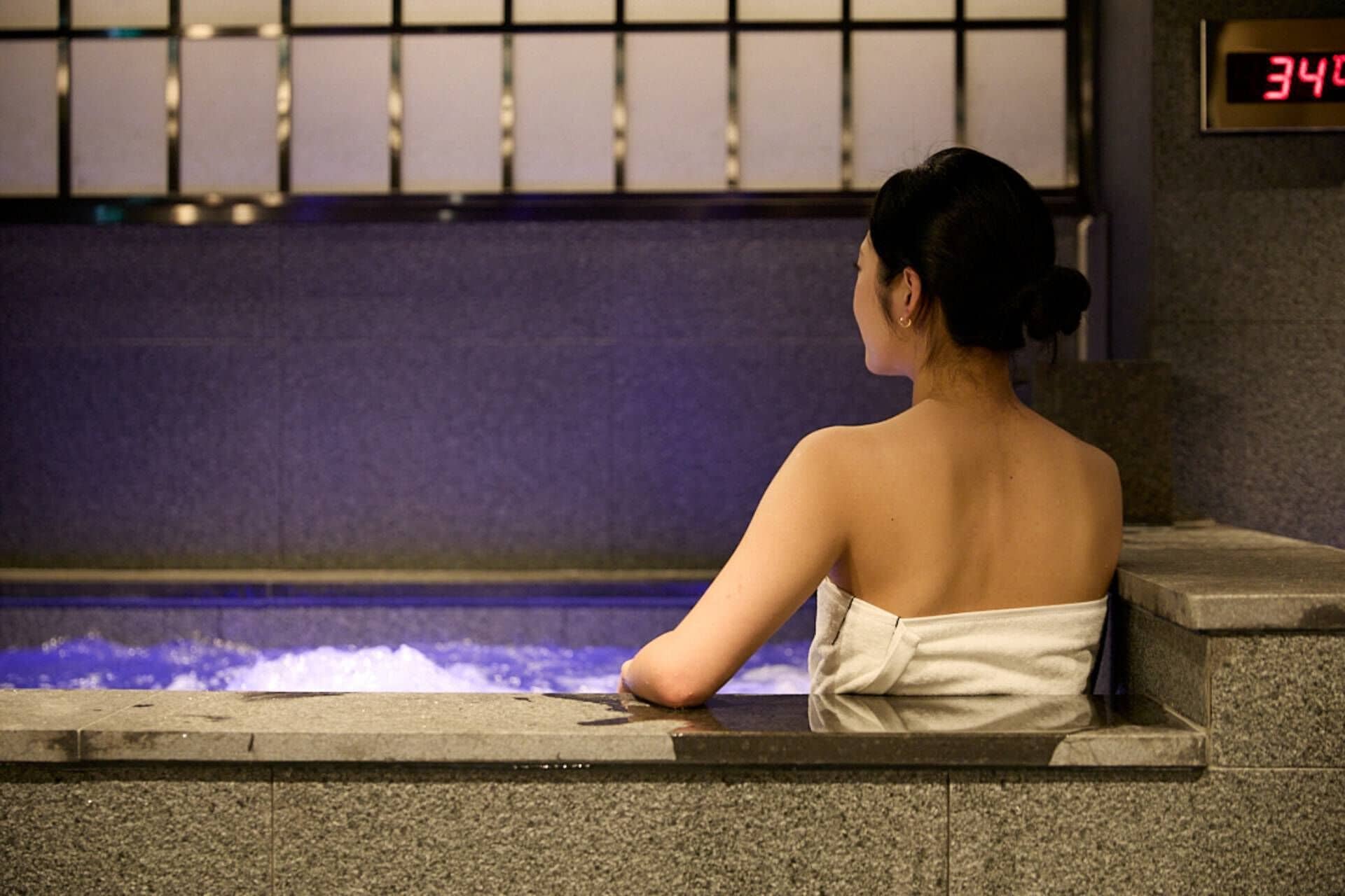 A person sitting by a pool with a digital clock displaying 3:40.