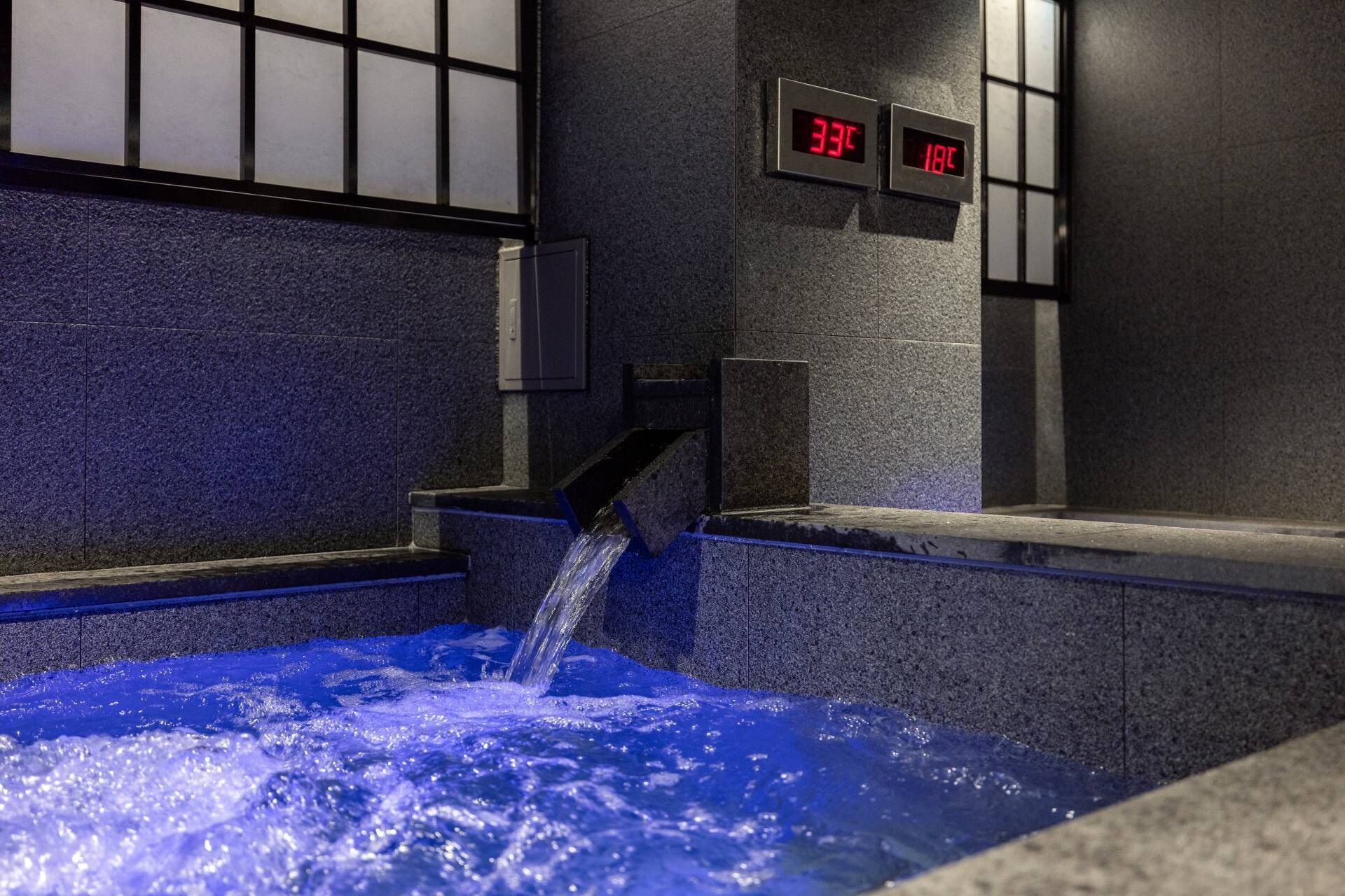 Un bain à remous équipé d’un thermomètre numérique affichant 33 °C et 18 °C.