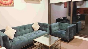 Una sala de estar con sofá, sillón y mesa de centro de vidrio.