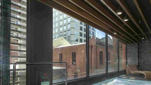 Un área de spa con un jacuzzi, ventanas amplias y vistas a la ciudad.