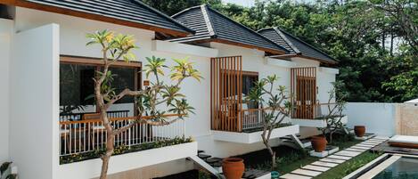 A modern house with a pool, featuring a white exterior, wooden balconies, and potted plants.