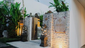 A stone wall with a sign reading "SANJULA" and a small statue. - Sanjula Uluwatu (Uluwatu)