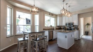 A spacious kitchen with a central island, white cabinetry, and pendant lighting.