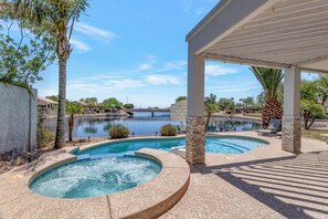 A swimming pool area with a hot tub, a covered patio, and a view of a lake. - Lakefront home w/ Kayaks, Private Pontoon Boat, Heated Pool & Spa! Pool table + Free Golf! (Glendale)