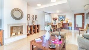 A spacious living room with a fireplace, dining area, and a large mirror on the wall. - Villa in Empuriabrava with Private Pool & Mooring (Empuriabrava)