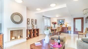 A spacious living room with a fireplace, dining area, and a large mirror on the wall.