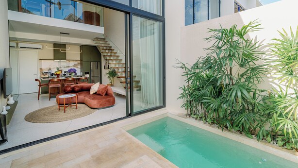 Ein modernes Haus mit einem wintergartenartigen Essbereich, einem Pool und einer Treppe, die zu einer oberen Etage führt.