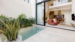 Ein modernes Wohnzimmer mit Pool, einer Couch und einem Essbereich.