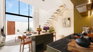 Eine moderne Küche mit einer zentralen Kochinsel, einem Essbereich mit Stühlen, einem großen Fenster und einer Treppe.