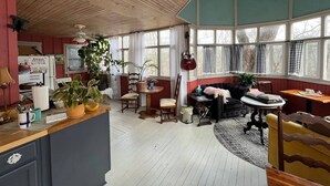 A cozy, well-lit room with a wooden ceiling, a dining area, and a seating area with a sofa and chairs.