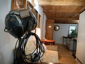 Une pièce avec un ventilateur de plafond, un canapé, une petite table et un miroir au mur.