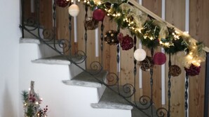 Una escalera con barandilla de madera, adornada con guirnaldas y adornos.