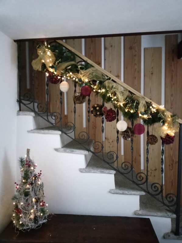 A staircase with a wooden railing, decorated with garlands and ornaments. - Adamossi Lombardini Completely renovated historic house in Sluga Valley.  (san giacomo filippo)