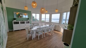 A dining area with a table set for six, white chairs, and hanging wicker lamps. - GITE LE GRAND BLEU (Ploubazlanec)