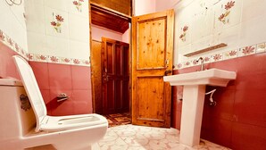 A bathroom with a toilet, sink, wooden door, and tiled walls.