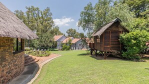 A thatched-roof building adjacent to a brick structure, both with visible steps leading to the entrance. - Grand Manor  (Muldersdrift)