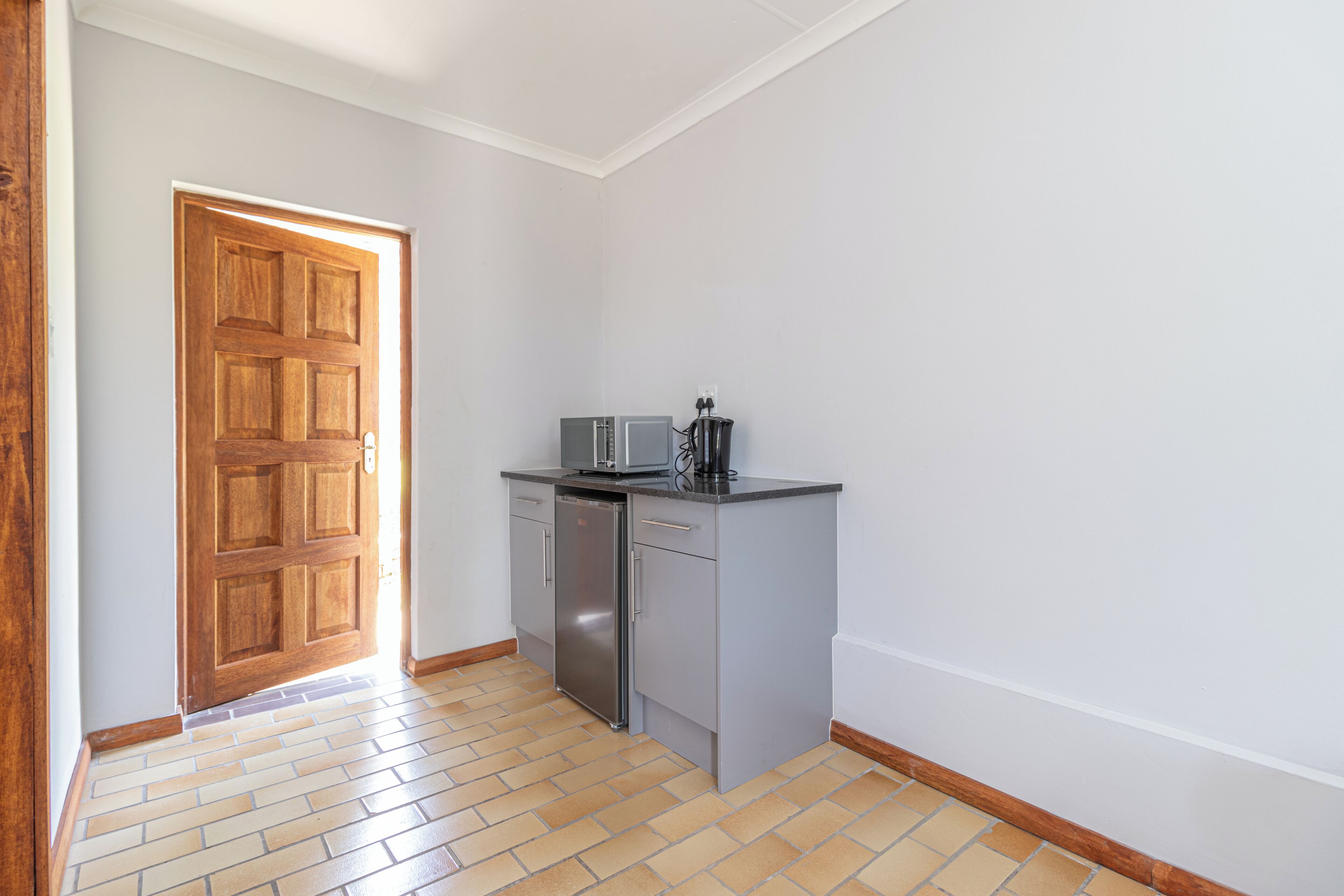 A kitchen with a built-in microwave, a coffee maker, and a refrigerator.