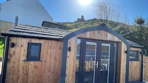 En træhytte med skråt tag, store glasdøre og en terrasse.