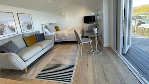 Et moderne soveværelse med seng, sofa, et lille bord og et fjernsyn.