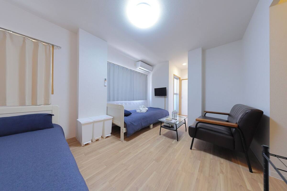 Habitación de hotel compacta con una cama individual, un escritorio, una silla y un televisor.
