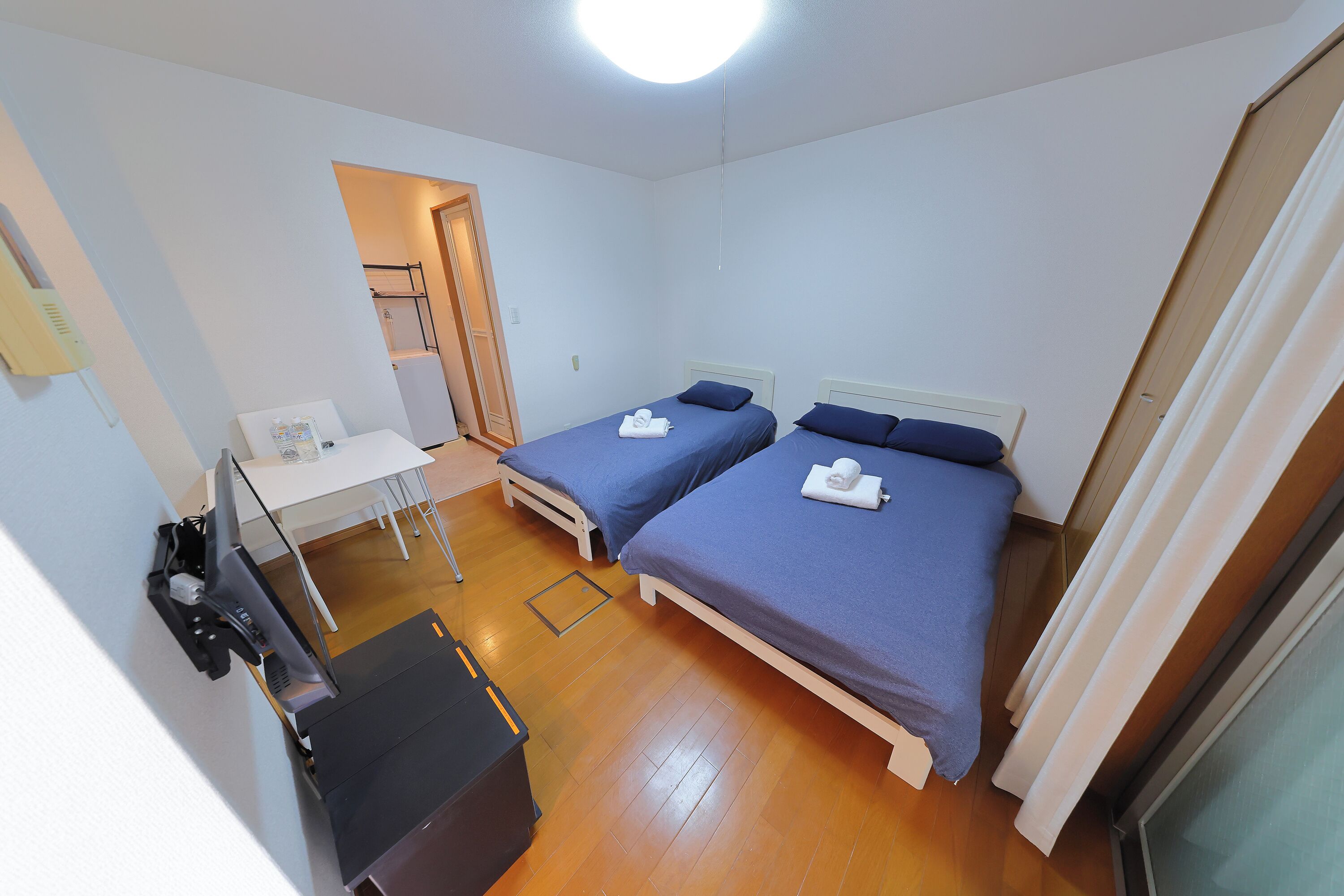 Una habitación pequeña y limpia con dos camas, un escritorio y una silla.