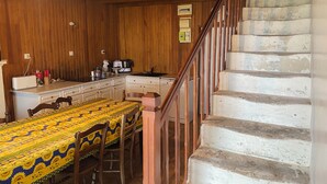 Una cocina con paredes de madera, una mesa de comedor con mantel amarillo y una escalera con barandilla de madera.