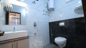 Une salle de bain moderne avec un lavabo blanc, des toilettes, une douche et un sèche-cheveux fixé au mur.