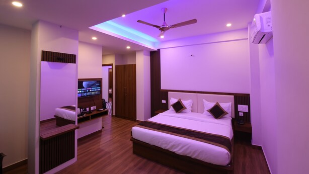 Une chambre d’hôtel moderne dotée d’un grand lit, d’un ventilateur de plafond, d’un éclairage encastré, d’une télévision et d’un plancher en bois.