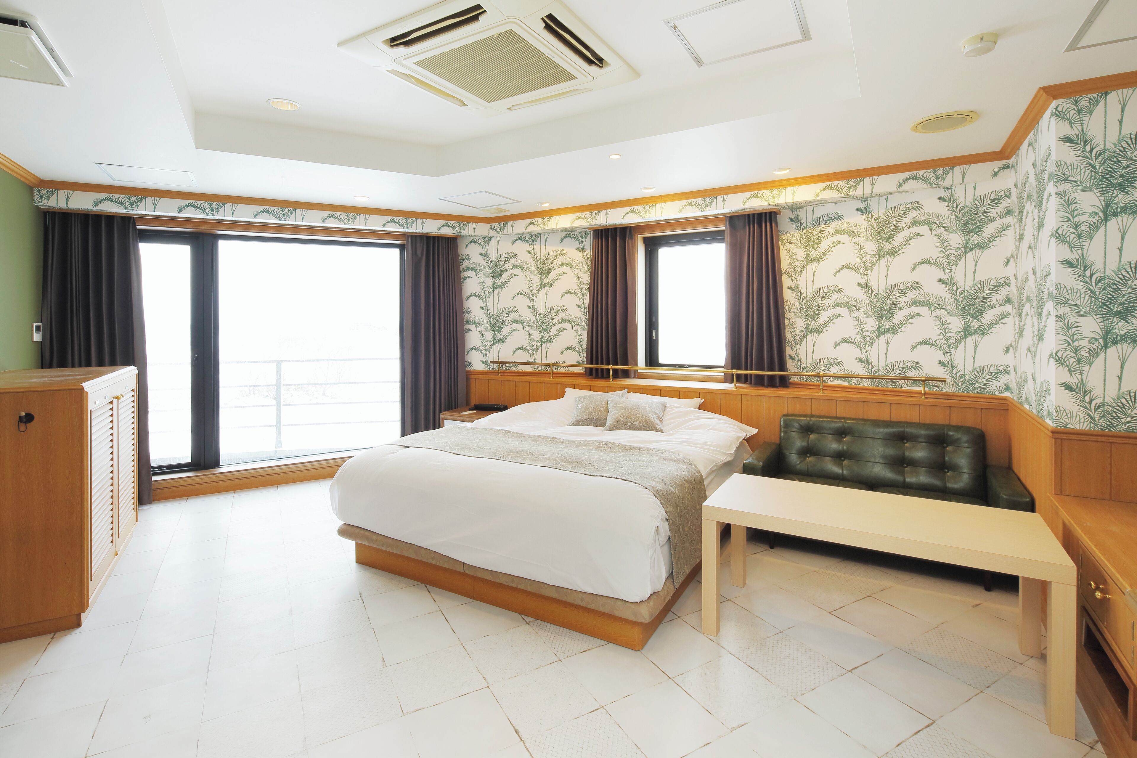 A modern hotel room with a large bed, a desk, and a view of the city.